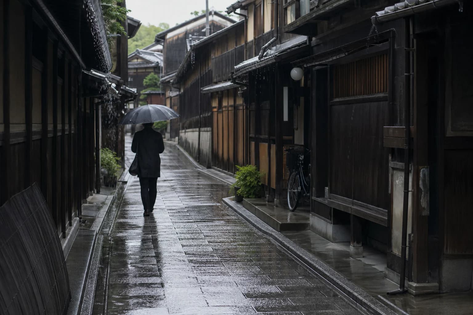 Yağmur sonrası Kyoto'nun ahşap evli dar bir sokağında şemsiyeyle yürüyen kişi