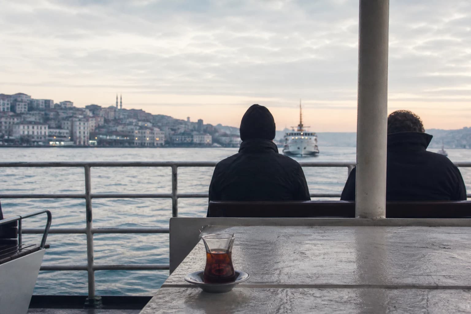 Sabah ışığında İstanbul vapurunun açık güvertesinde çay ve iki yolcu