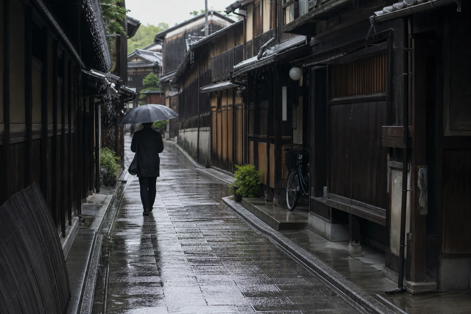Yağmur sonrası Kyoto'nun ahşap evli dar bir sokağında şemsiyeyle yürüyen kişi