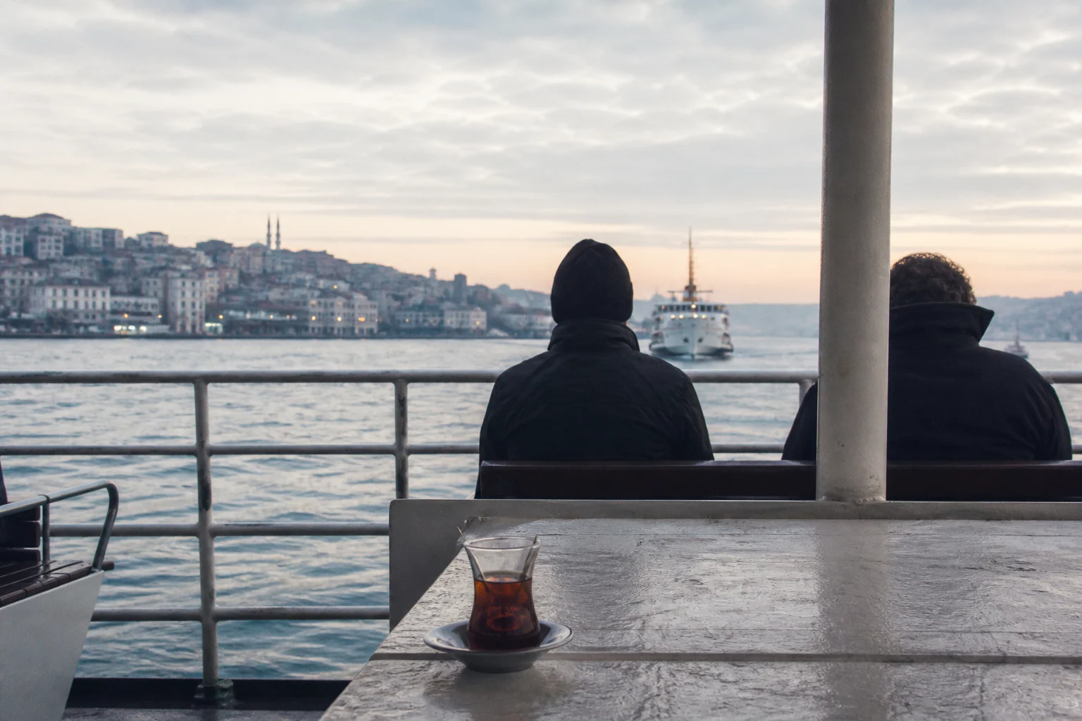 Sabah ışığında İstanbul vapurunun açık güvertesinde çay ve iki yolcu